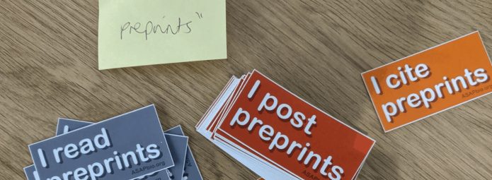 Preprint stickers on a table with a post-it note that says "I screen preprints"