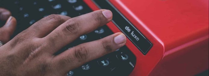 Stock photo of hands typing on a red typewriter