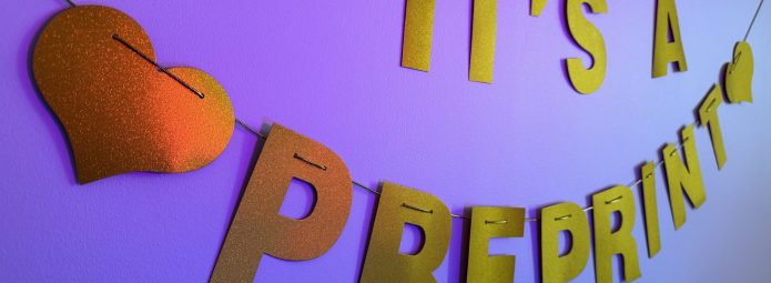 Photo of a gold party banner that says "it's a preprint" illuminated by colored lights